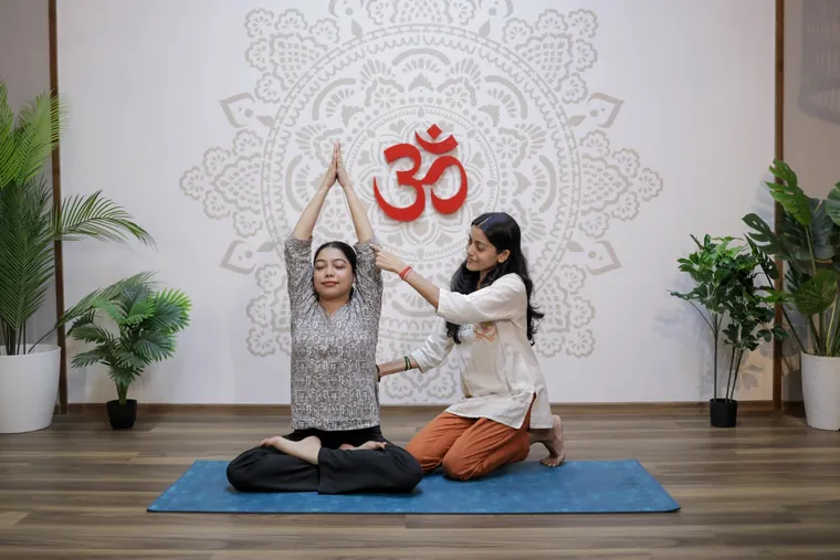 Sayali Vaidya guiding a woman through a gentle fertility yoga posture in a calm studio